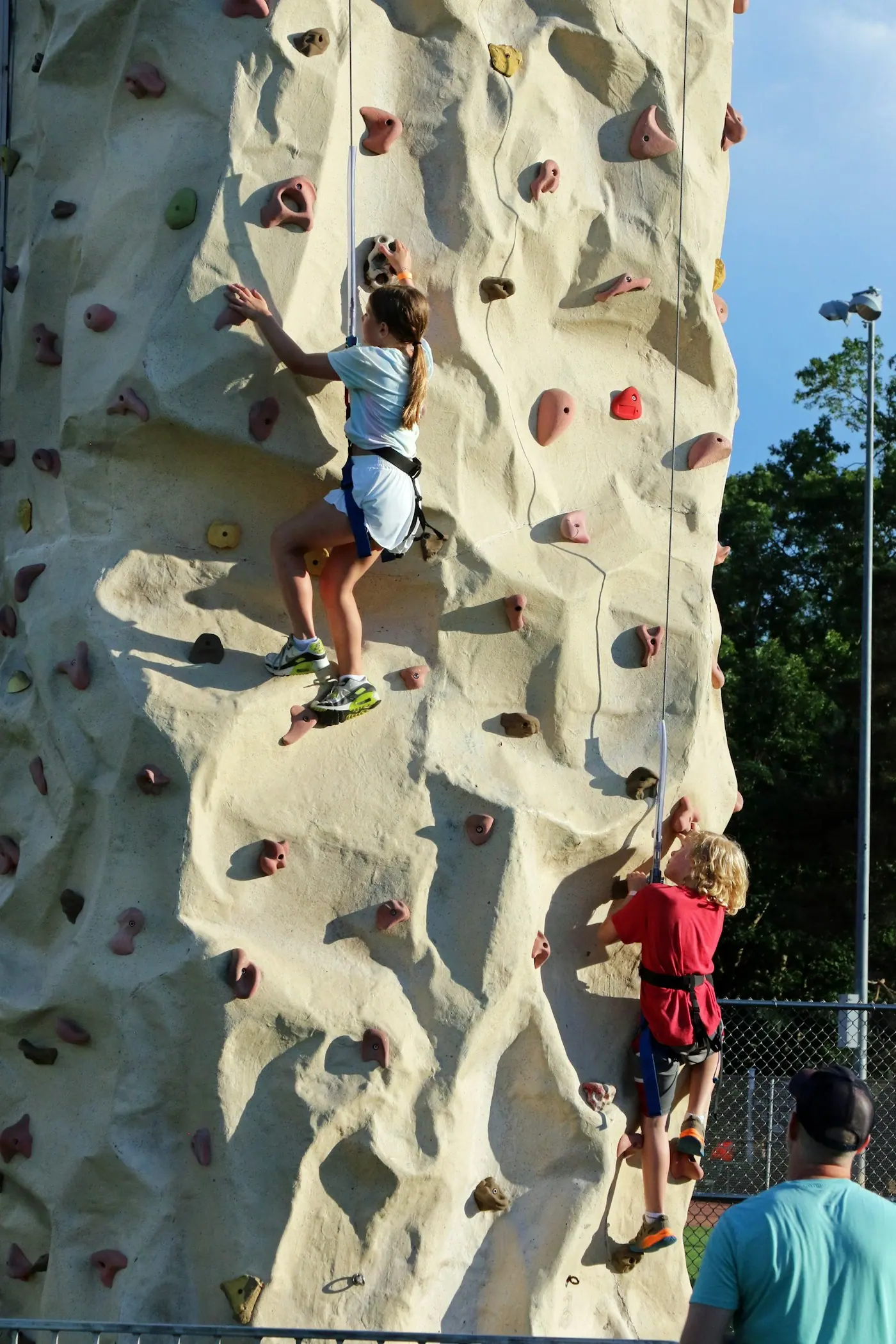 Children climbing a tall artificial climbing wall together